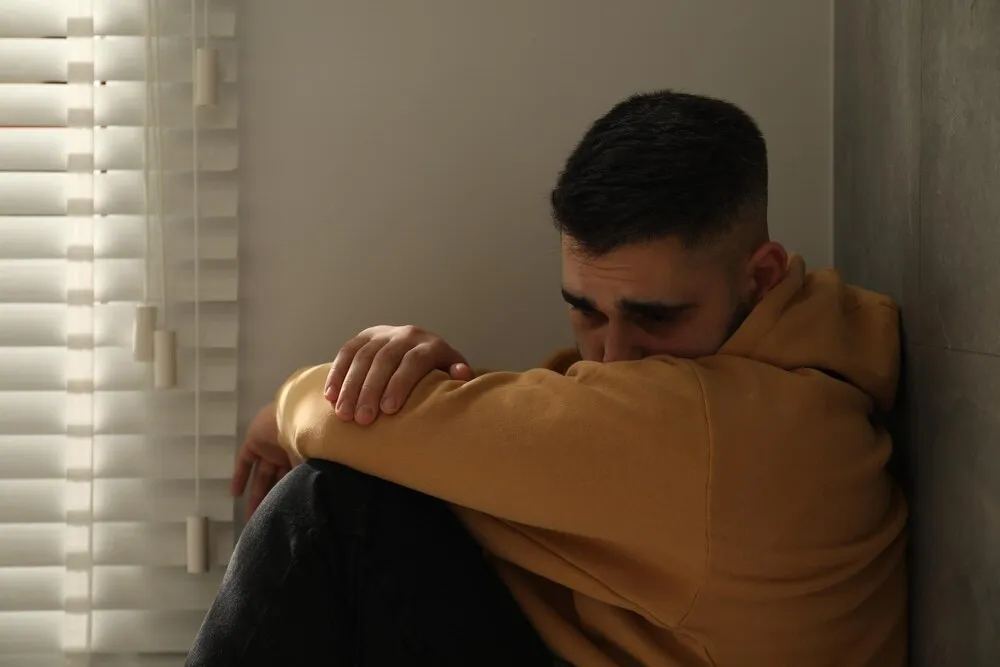 hombre triste sentado cerca de la ventana en casa