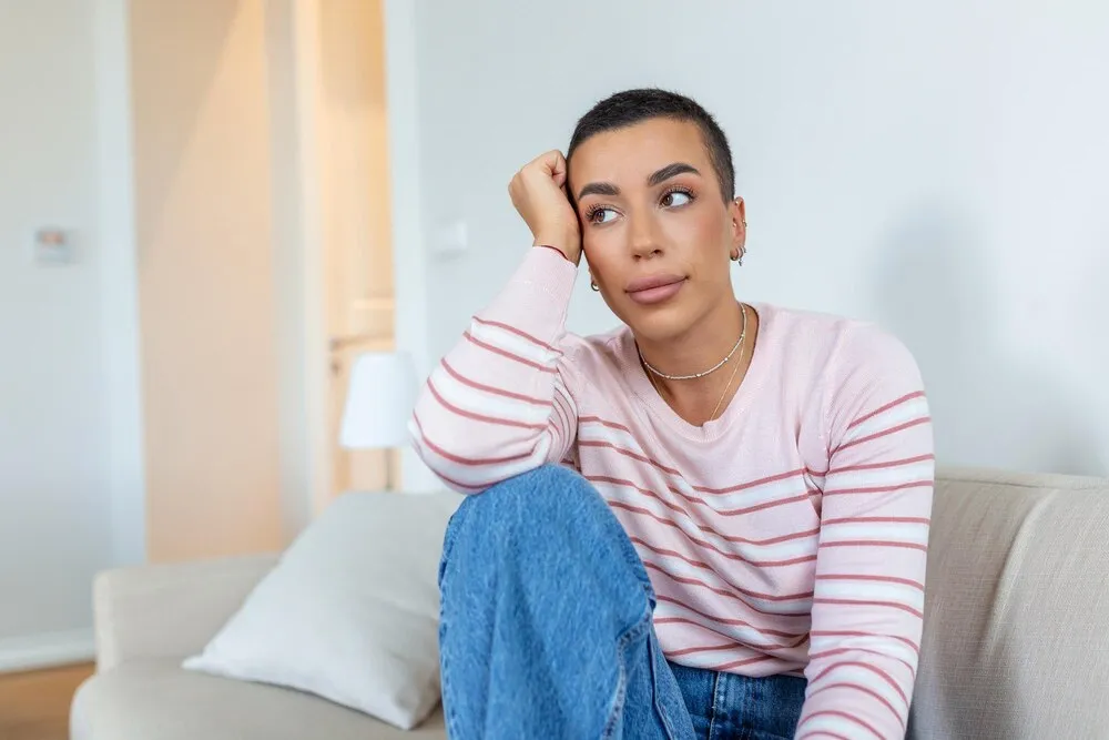 mujer joven relajándose en su sofá en casa en la sala mujer hermosa sola en la sala mujer africana sonriente sentada en el sofá