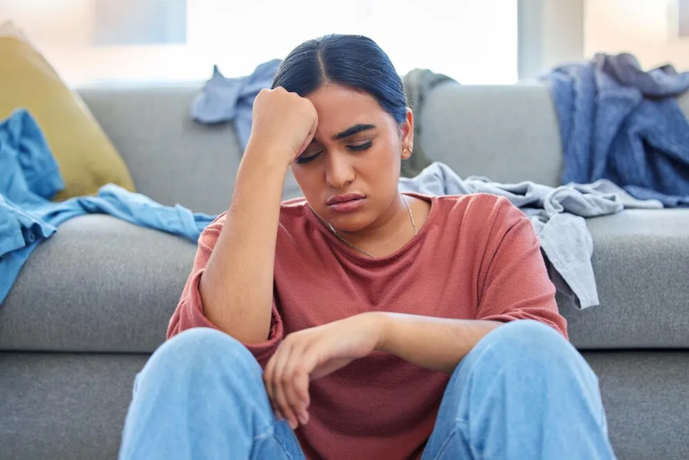 dolor de cabeza depresión y mujer con estrés por lavar la ropa en una sala agotada e infeliz en su hogar ansiedad migraña y mujer abrumada con las tareas del hogar o la limpieza de primavera