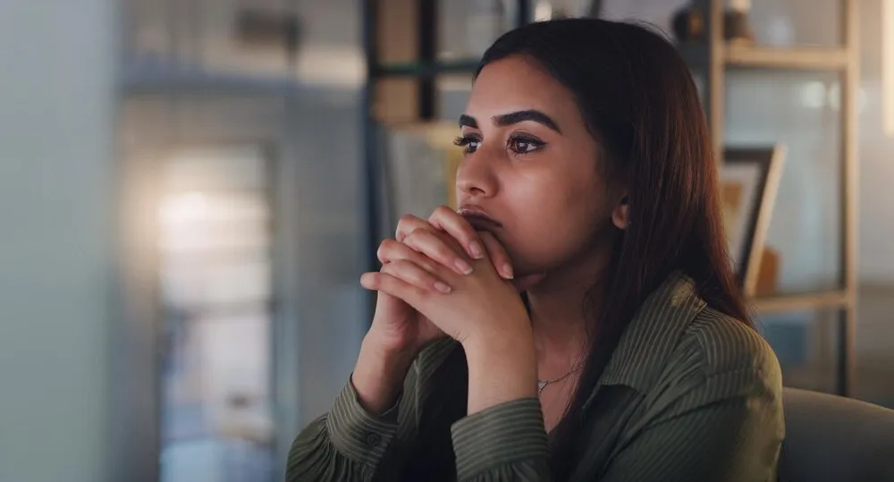 mujer de negocios pensando y computadora de noche en la oficina con ansiedad, estrés o crisis; emprendedora en el escritorio con tecnología mientras está cansada o preocupada por una fecha límite, un error o un problema de salud mental