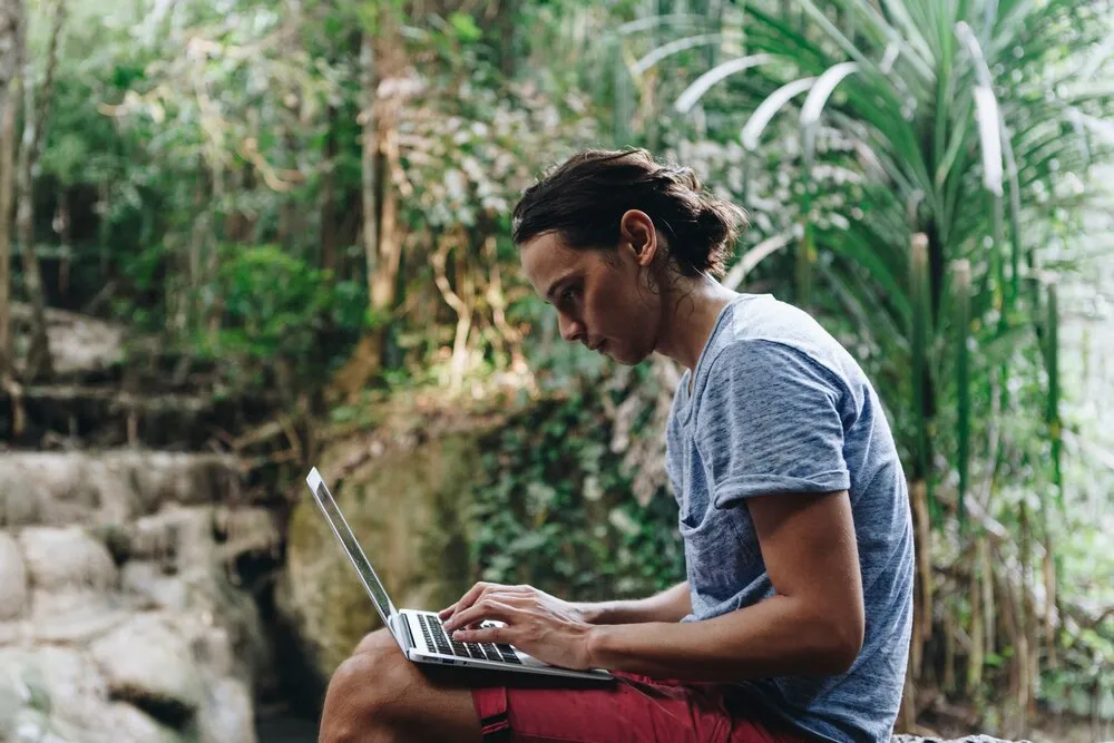 hombre blanco usando una computadora portátil en una cascada
