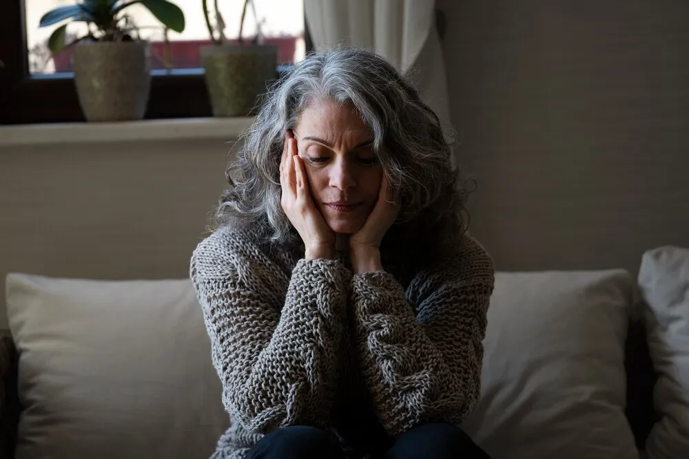 mujer mayor triste en el sofá