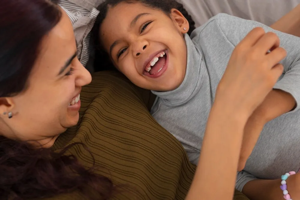 Vista superior de madre haciéndole cosquillas a una niña.