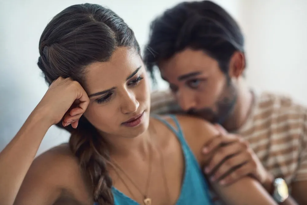 infelicidad, molestia o tristeza con una pareja peleando en un sofá en la sala de su casa por una infidelidad o ruptura, depresión, abuso o conflicto con una mujer triste pensando en el divorcio mientras discuten.