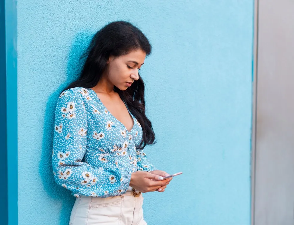 Mujer con blusa de flores trabajando en su celular