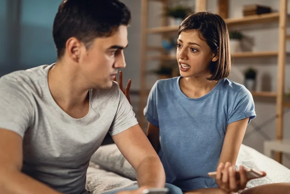 Pareja joven teniendo un conflicto y discutiendo en la recámara, el enfoque está en la mujer.
