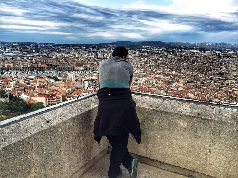 vista trasera de un hombre mirando el paisaje urbano desde una terraza