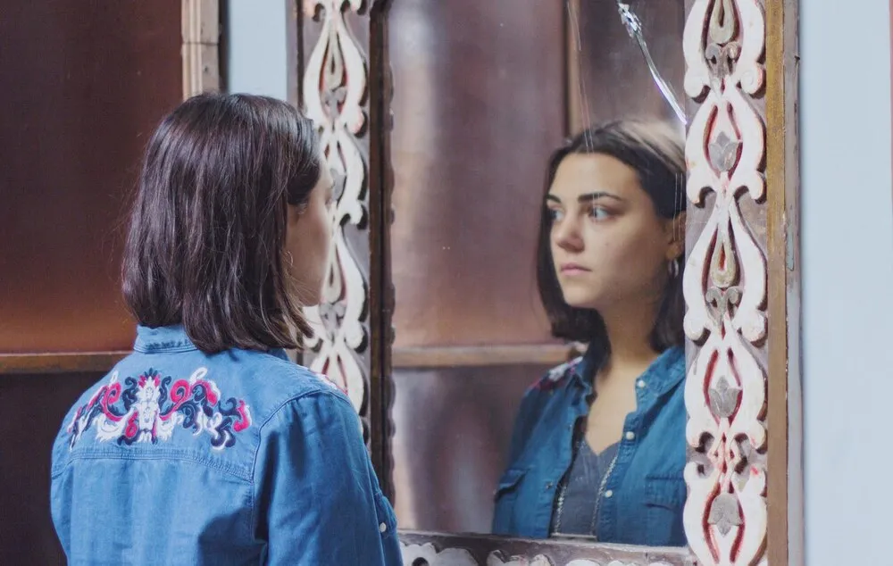 mujer joven reflejándose en el espejo