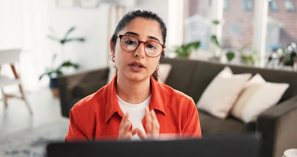 trabajo remoto por computadora y videollamada con una mujer en la sala de su casa para una discusión o conversación de planeación, laptop y reunión virtual con empleada freelance en un departamento para contacto o actualización