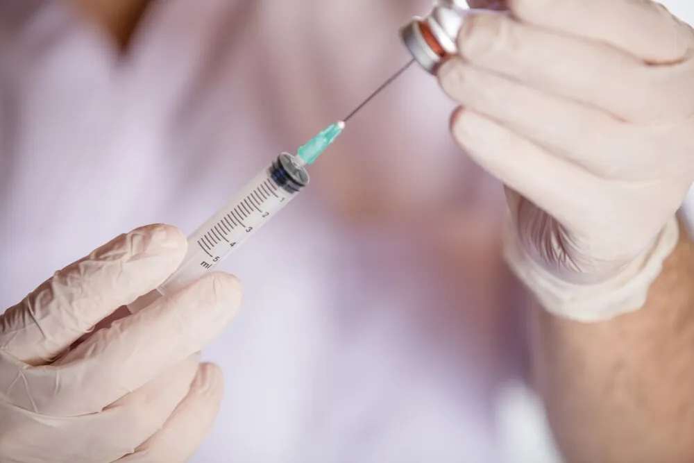 trabajador de la salud extrayendo vacuna de un vial a una jeringa para COVID-19