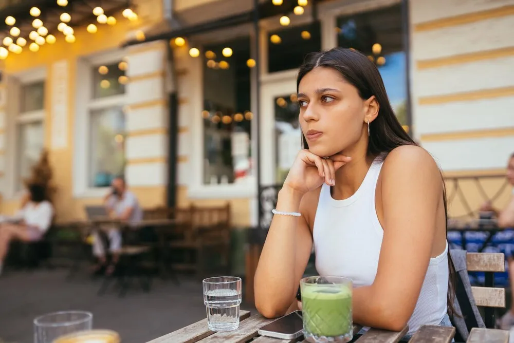 Mujer cansada y triste a la moda descansa en una cafetería acogedora.